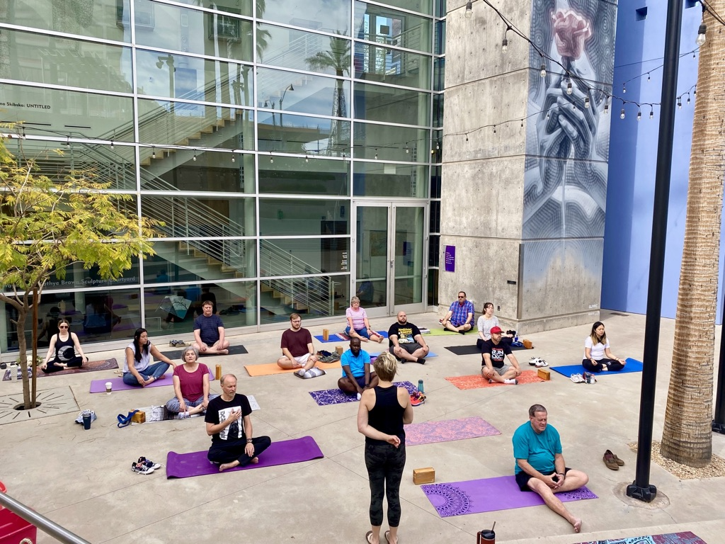 A group practicing accessible yoga together in an urban courtyard