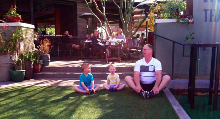 An adult sitting with two children on the Postino East lawn
