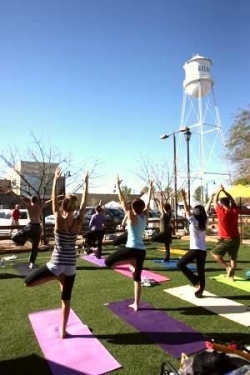 A yoga group practicing beneath a water tower near Postino East